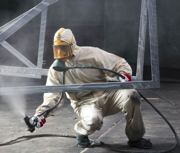 cat epoxy besi Seorang teknisi menggunakan alat semprot untuk mengaplikasikan cat epoxy pada struktur baja, mengenakan pakaian pelindung lengkap dan respirator untuk keamanan saat proses coating baja terbaik.