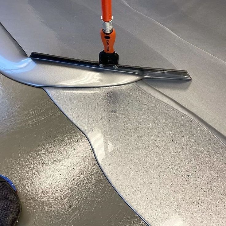 Cat Epoxy Aplikasi epoxy lantai anti slip menggunakan rakel oleh teknisi profesional untuk meningkatkan keamanan dan daya tahan permukaan lantai industri.