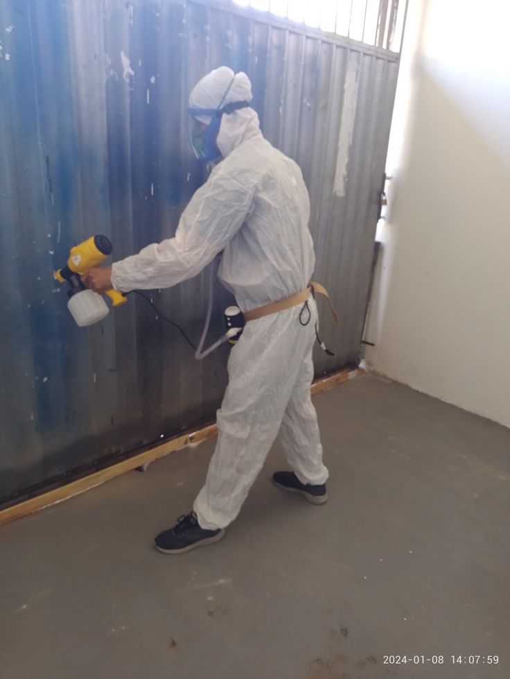 Teknisi menyemprotkan protective coating sebagai pelapis anti karat untuk mencegah korosi pada permukaan struktur baja di area industri.